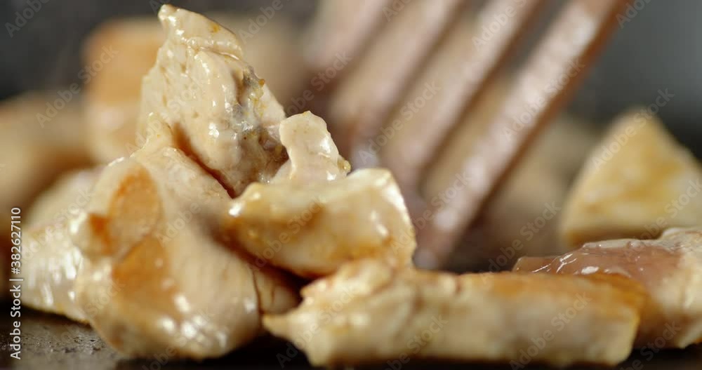 Pieces of chicken fillet are stirred with a spatula in pan. Pieces of chicken fillet are stirred with a spatula in pan.