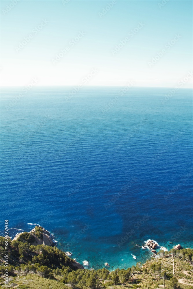 Mar azul de agua cristalina con rocas y la luna creciente