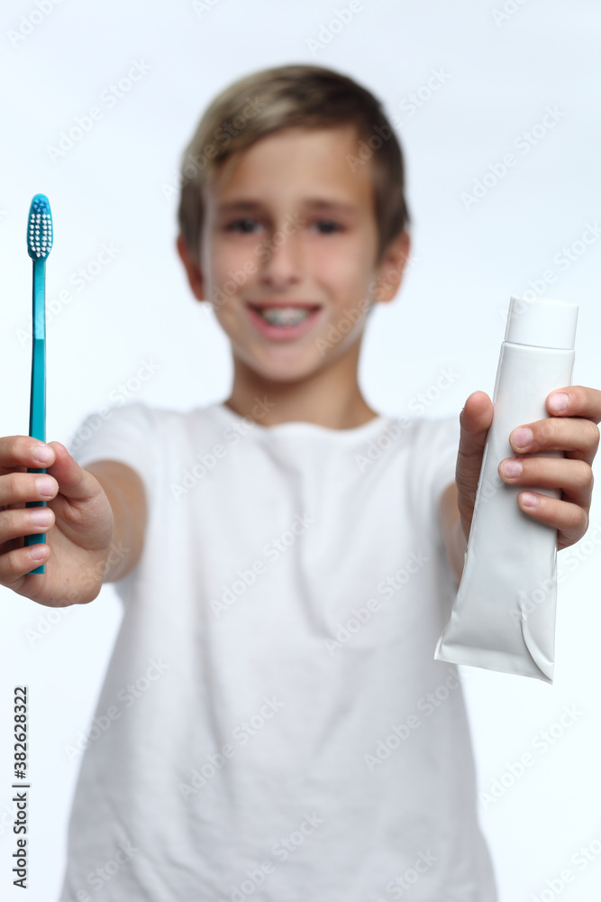 boy in white t-shirt squeezes toothpaste on brush and prepares to brush his teeth. boy in white t-shirt squeezes toothpaste on brush and prepares to brush his teeth.