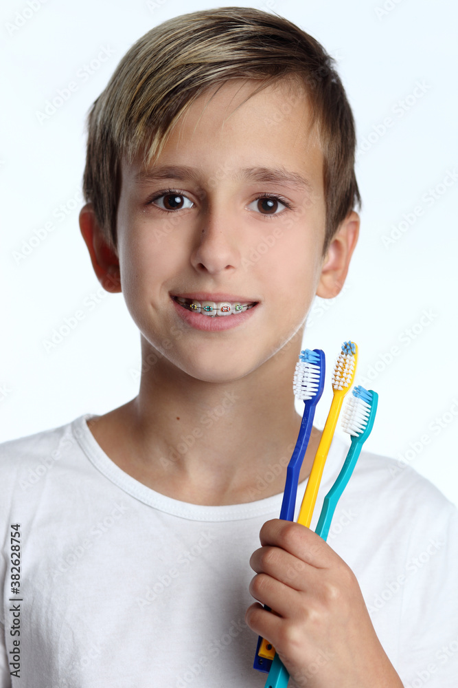 Portrait of a boy holding a tooth brush over white background Portrait of a boy holding a tooth brush over white background