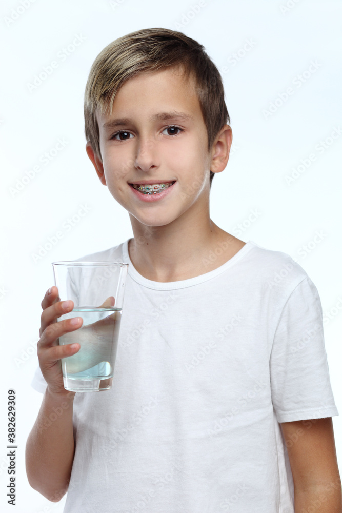Cute boy with white background, wearing braces on his teeth. Spray a disinfectant mouthwash in the throat. Cute boy with white background, wearing braces on his teeth. Spray a disinfectant mouthwash in the throat.