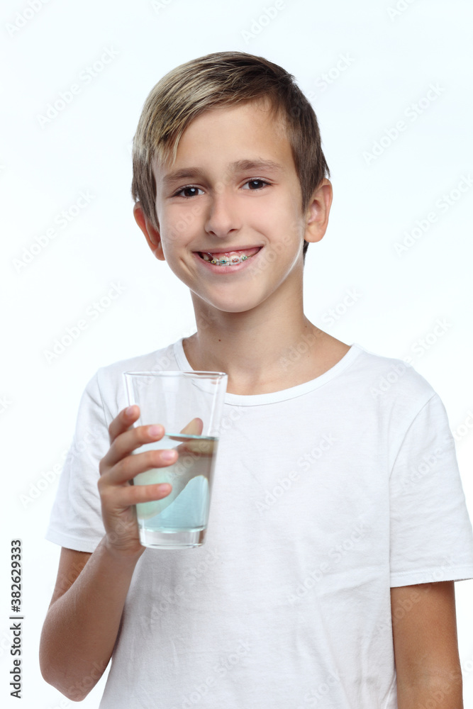 Cute boy with white background, wearing braces on his teeth. Spray a disinfectant mouthwash in the throat. Cute boy with white background, wearing braces on his teeth. Spray a disinfectant mouthwash in the throat.