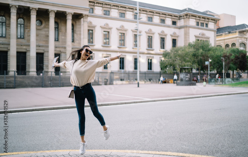Overjoyed asian female in casual wear jumping on street feeling carefree and amazing with visiting destinations, young woman tourist enjoying journey and city leaping on urban setting background