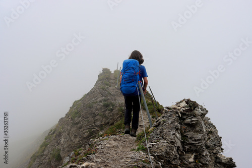 Boy on a hiking trail surrounded by fog in the Swiss Alps. photo