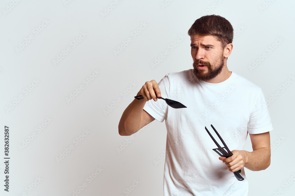 A man with kitchen appliances in the hands of their white T-shirt on a light background cropped view A man with kitchen appliances in the hands of their white T-shirt on a light background cropped view