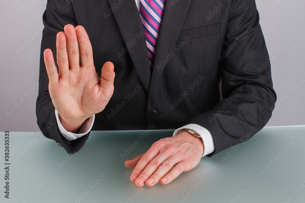 Obraz premium Close up businessman showing stop gesture with hand. Businessman saying stop holding his hand in front of him sitting at table.