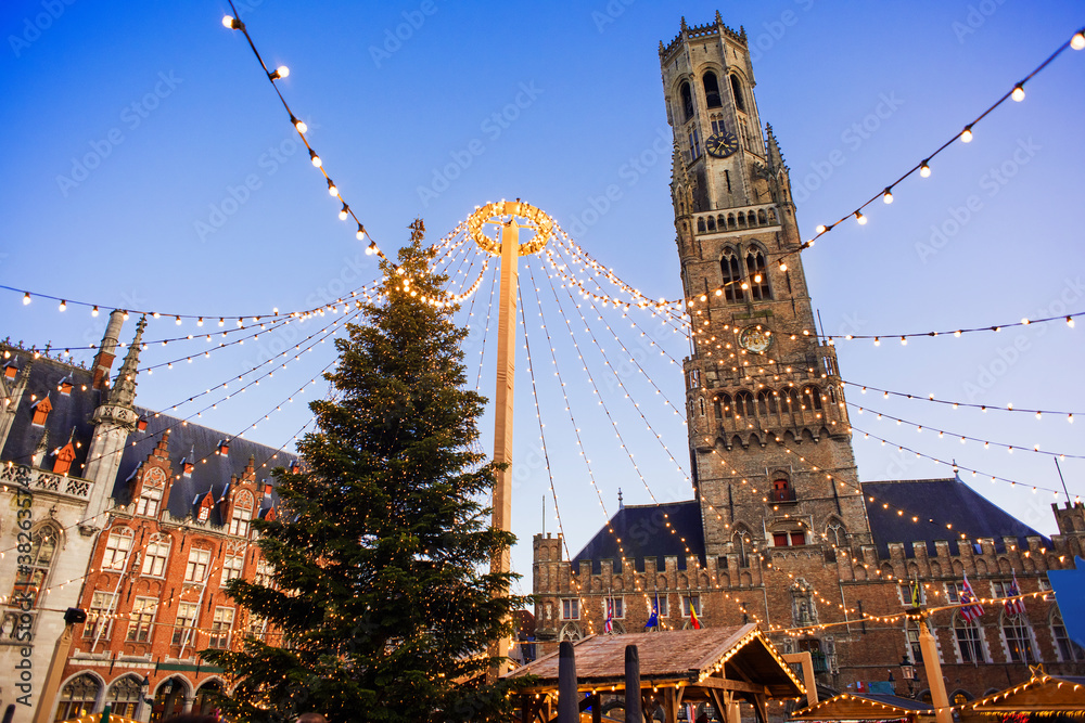 Fototapeta premium Traditional Christmas market in Europe, Bruges, Belgium. Main town square with decorated tree and lights. Christmas fair concept