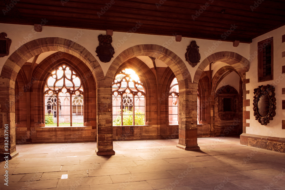 Sunlight in inner cloister, archway with collumns and openwork windows. Cathedral in Basel, Switzerland.