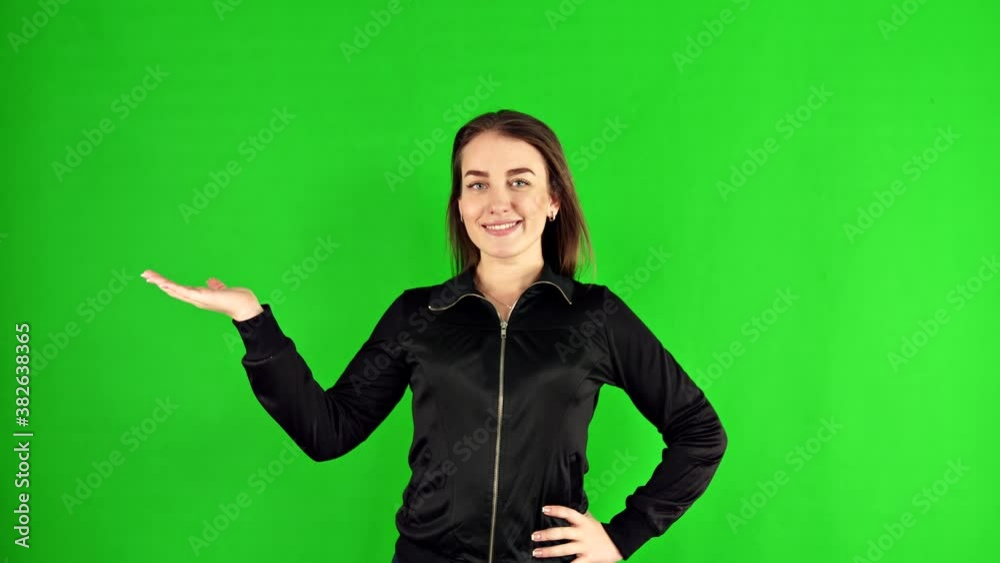 A woman on a green background holds her hand palm up A woman on a green background holds her hand palm up
