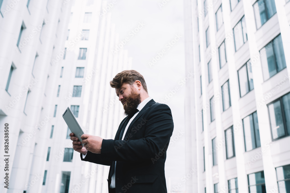 Serious entrepreneur looking at digital tablet on street Serious entrepreneur looking at digital tablet on street