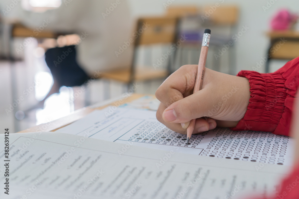 Hand Student use pencil writing on paper optical form of standardized test examination, Answer sheet,doing final exam attending in examination classroom Hand Student use pencil writing on paper optical form of standardized test examination, Answer sheet,doing final exam attending in examination classroom