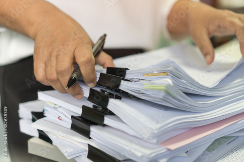 Office workers arranging stacks of lot documents report papers with clips waiting be managed on desk in busy office. Concept of workload in business finacial paperwork information planing