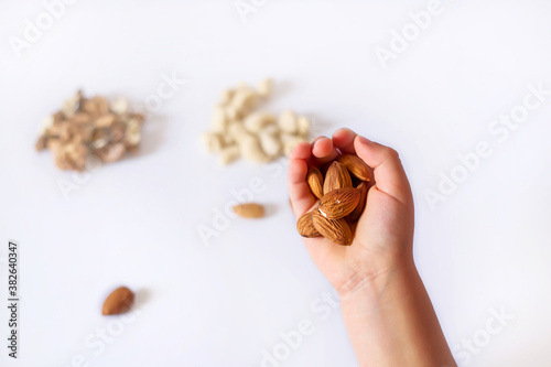 Walnut in hand.
Hold the nut with your fingers.
The child holds nuts in his hand. 
Nuts on a white background.

Walnuts.
Walnut and cracked walnut. Fresh walnuts. Walnuts for sale
 Almonds in hand.