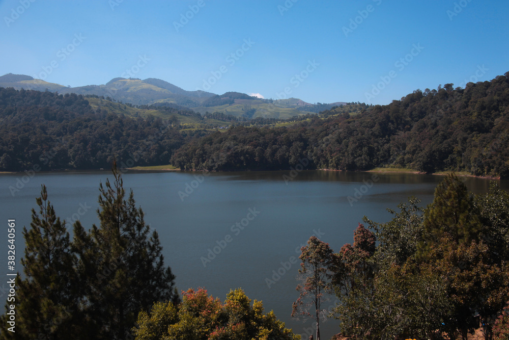 Beautiful lake in the middle of forest, with hill in the background on bright sunny day. Beautiful lake in the middle of forest, with hill in the background on bright sunny day.
