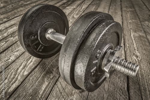 iron dumbbell on a grunge wooden deck - fitness concept, black and white image