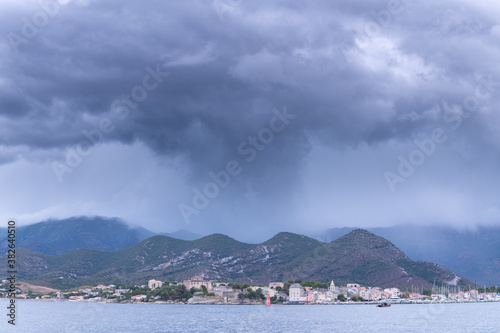 A dark cloud pouring rain over the village of Saint Florent . Corsica