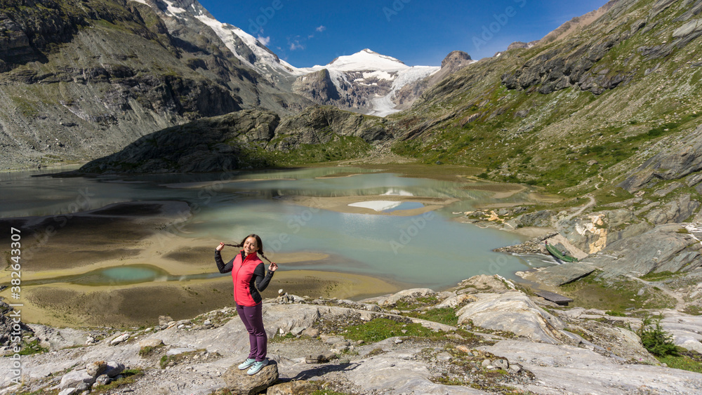 Girl on one of the best pristine hiking trails in Austria with glacier and crystal blue lake on background