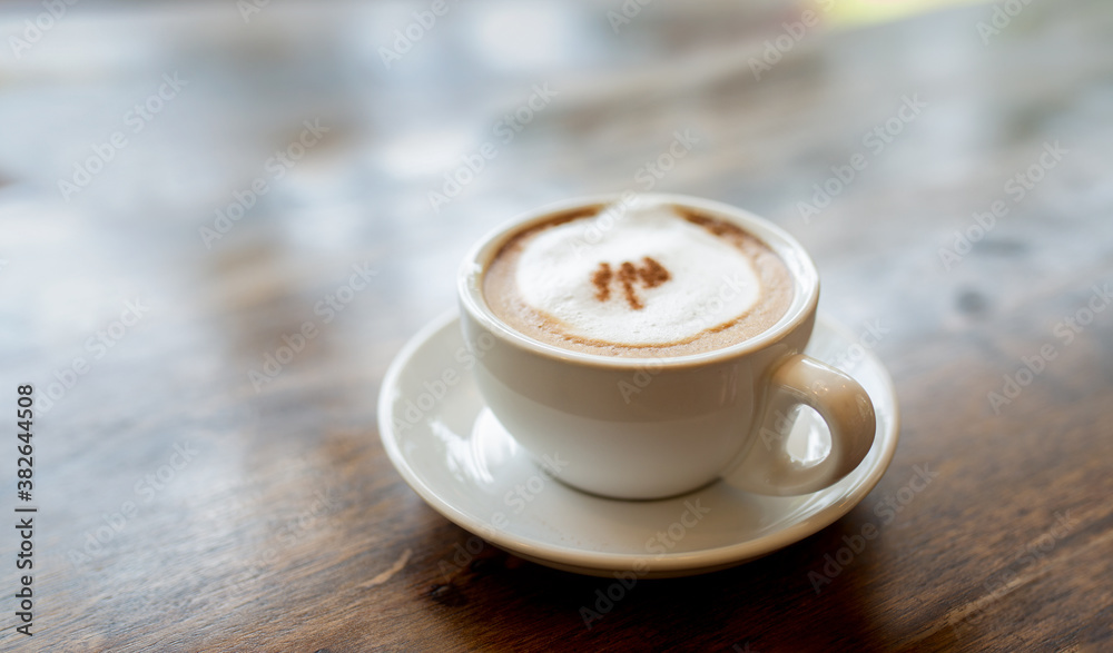White offee cup and hot cappuccino on wooden table blurred background. White offee cup and hot cappuccino on wooden table blurred background.