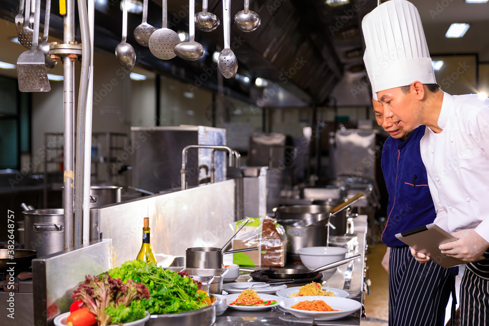 The male executive male discussing the menu with his colleague in the kitchen. The male executive male discussing the menu with his colleague in the kitchen.