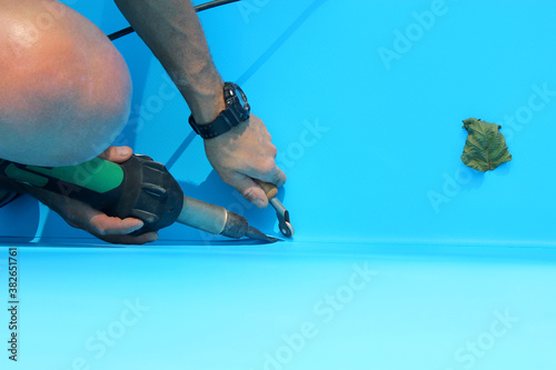 Photo A worker welds plastic cover for water pool