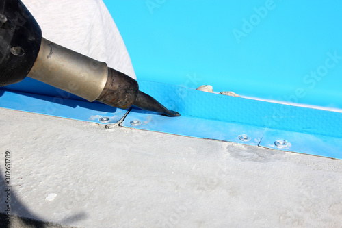 A worker welds plastic cover for water pool. Water pool cover replacement. Plastic Welding Machine. Swimming pool care concept.