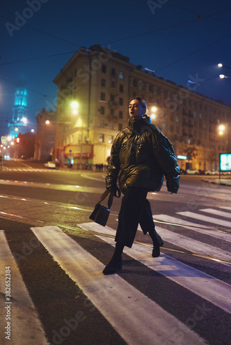 Model walking on crosswalk in city lights at night