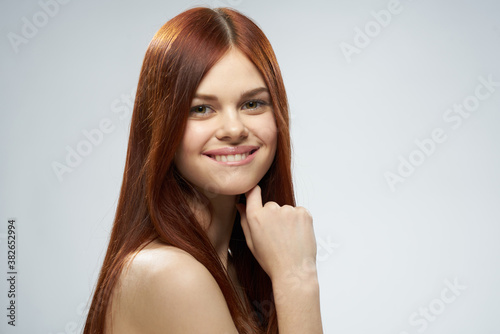 beautiful red-haired woman naked shoulders cosmetics long hair glamor light background