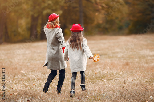 Fashionable mother with daughter. Family in a autumn park. Little girl in a red hat