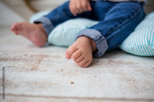 baby's legs in jeans close-up on a wooden background