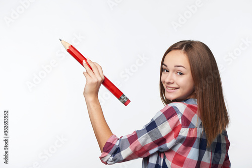 Teen girl writing with big pencil on copy space