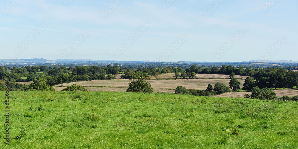 Scenic landscape view of grass fields with agricultural fieds beyond and a blue sky above