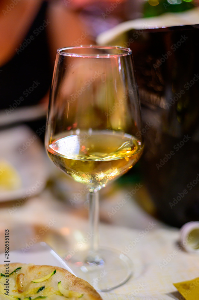 Glass of cold dry white wine served outdoor in cafe at night in Italy Glass of cold dry white wine served outdoor in cafe at night in Italy