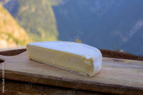 Cheese collection, French reblochon de savoie cheese served outdoor in Savoy region, with Alpine mountains peaks on background photo