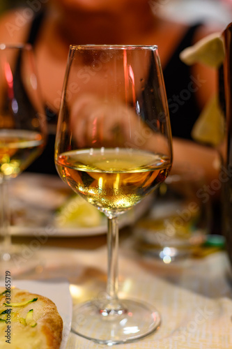 Glass of cold dry white wine served outdoor in cafe at night in Italy