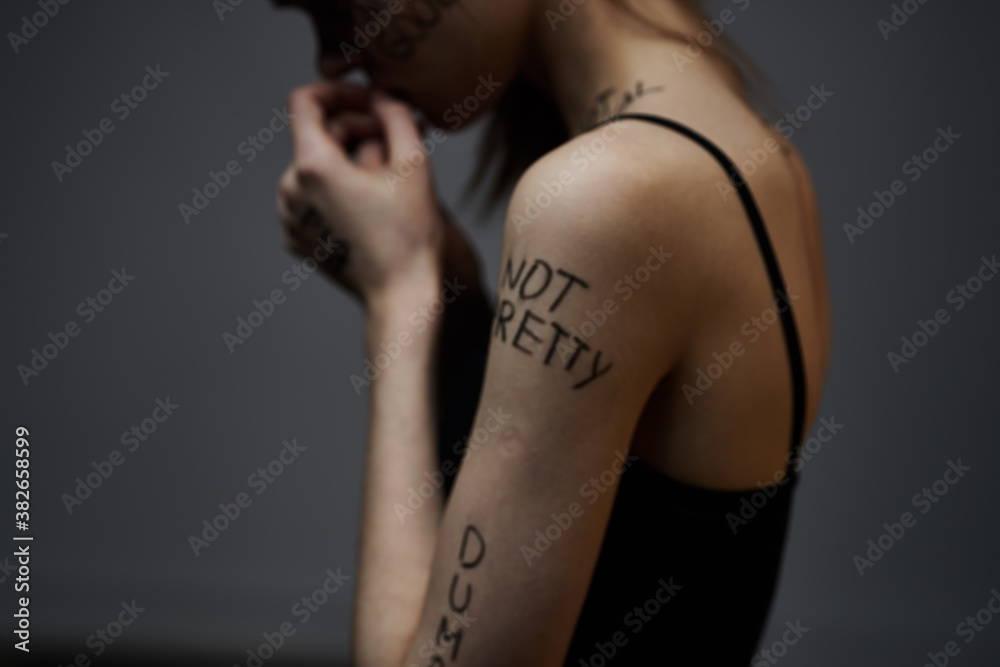 Woman with inscriptions on the body frustration and dissatisfaction emotions lifestyle gray background