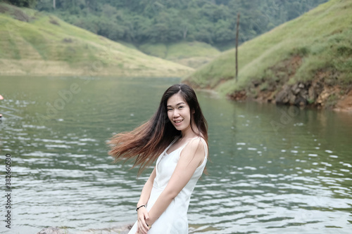 Asian woman wear white dress is smiling near the river in forest. Freedom life in nature Concept.