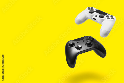 White and black game controllers on yellow background photo