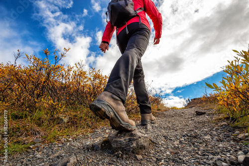 View of Woman Hiking Rocky Trail from Below during Fall in Canadian Nature. Taken in Tombstone Territorial Park, Yukon, Canada.