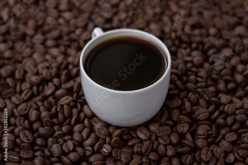 Hot black coffee in white cup on the coffee beans background  