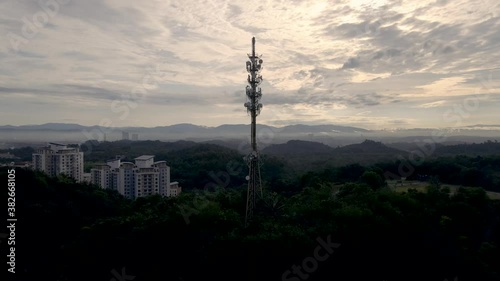 Aerial footage of Communication tower during morning sunrise with clouds, mists and fog. Reverse drone view