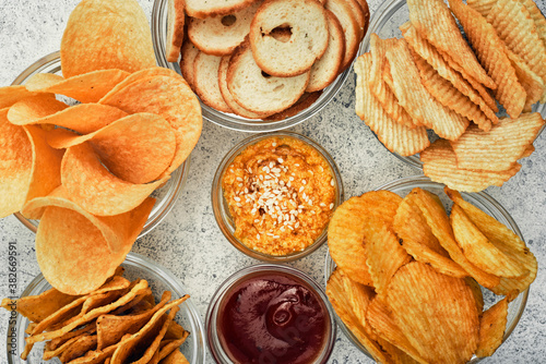 Vászonkép Potato and corn chips, snacks, crackers in transparent glass plates and sauces