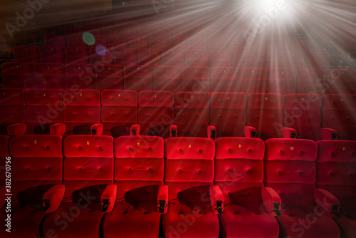 cinema hall with red armchairs and bright projector light
