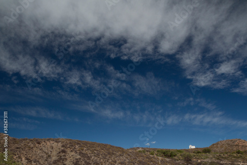 House of God. Allegoric view of a small chapel in the mountaintop under a beautiful deep blue sky with dramatic clouds.
