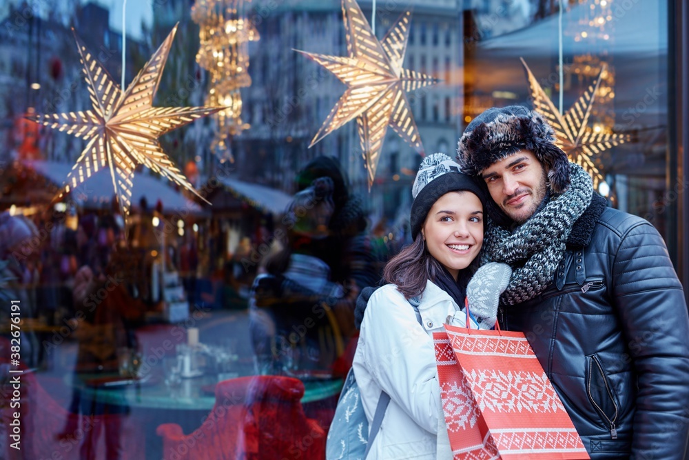 Young couple doing christmas shopping in the city, smiling, embracing.