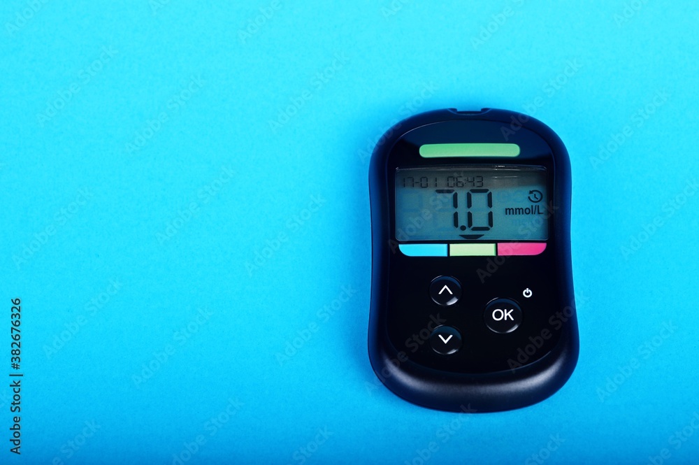 Black blood glucose meter shows high blood sugar content, lying on a blue background