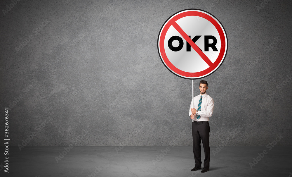 Young business person holdig traffic sign with OKR abbreviation, technology solution concept