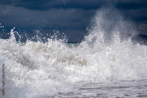 Storm at sea, waves crash on rocks.