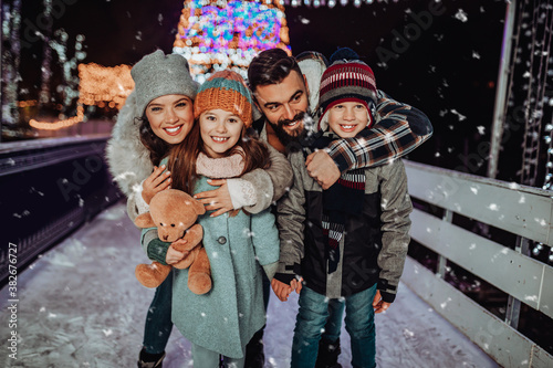 Happy young family having fun and enjoying in beautiful winter night at frozen skating park.