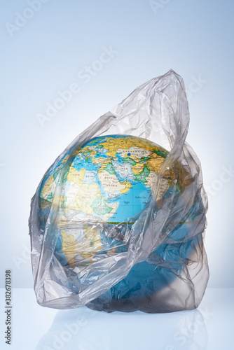 The concept of protecting the world from plastic waste, fighting environmental pollution, fighting for the environment, a globe in a black garbage bag on a light background.