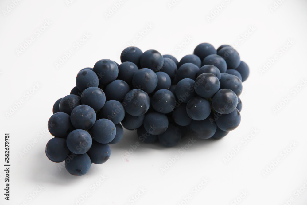 Black grapes, large fresh fruits with green leaves on a white background Black grapes, large fresh fruits with green leaves on a white background
